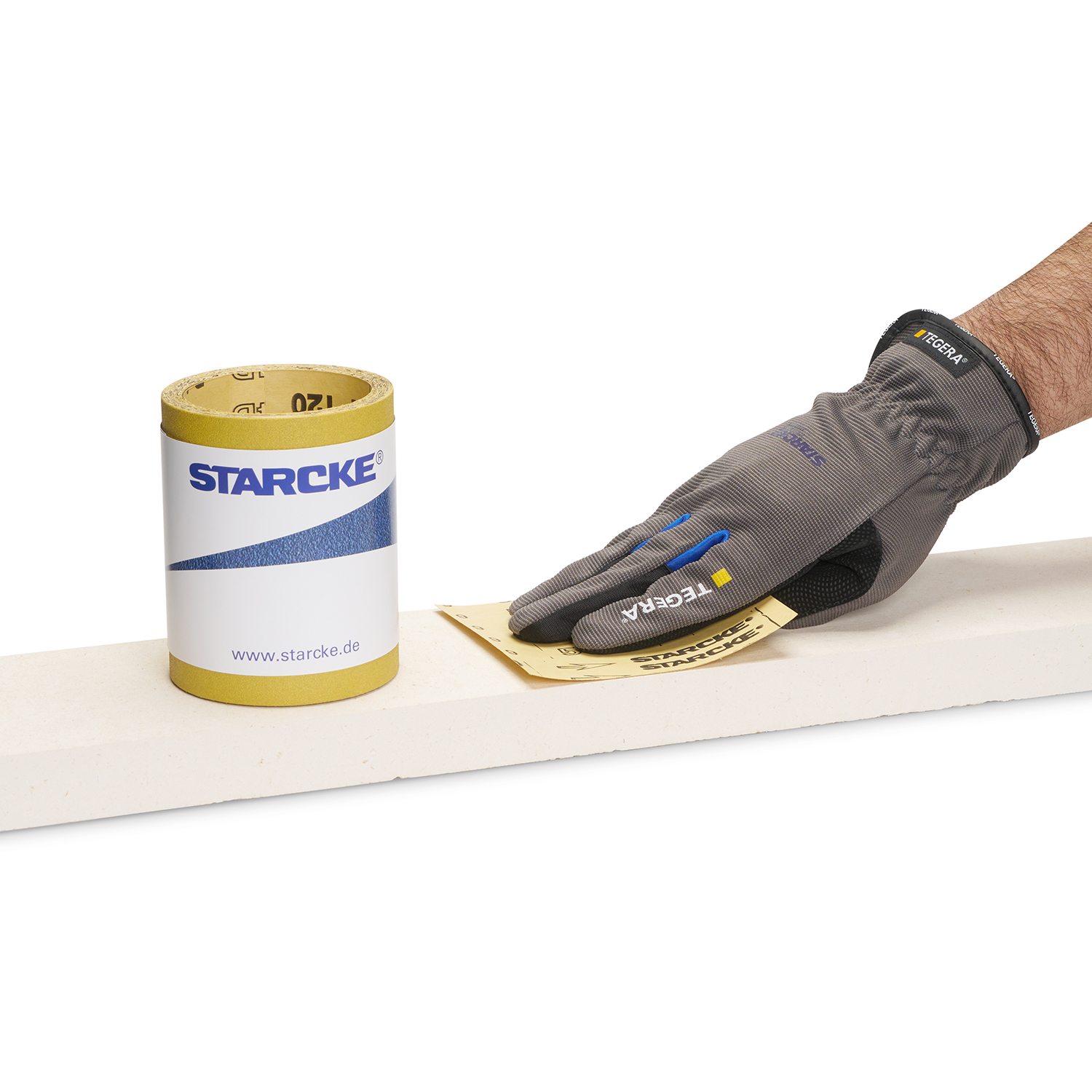 Schleifpapierrolle in gelb stehend auf Holz. Hand mit Schleifpapier im Hintergrund.