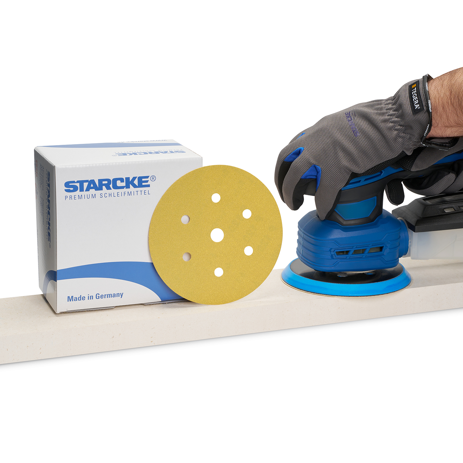 Schleifscheibe stehend vorm Produktkarton und daneben ein Schleifgerät